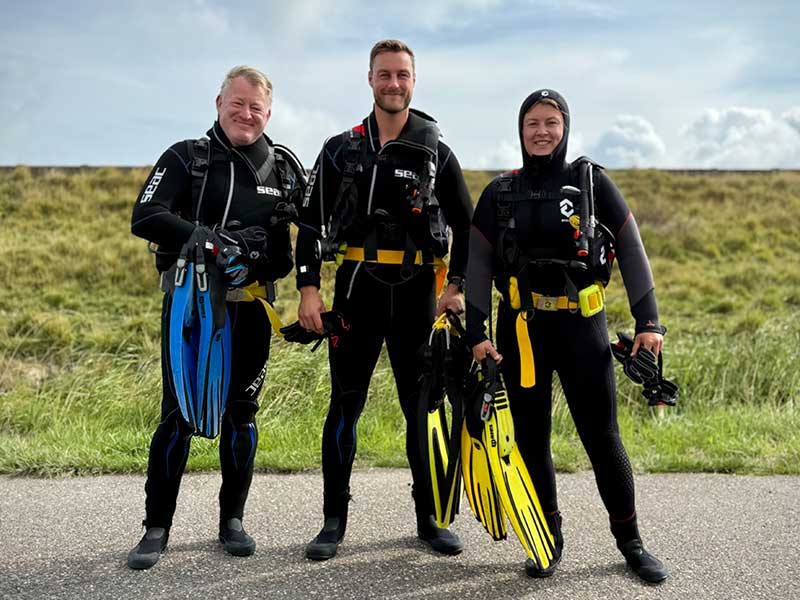 Three guided divers in diving equipment at the dive site